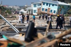 First responders and residents walk along a debris-littered street following Hurricane Michael, in Mexico Beach, Florida, Oct. 11, 2018.