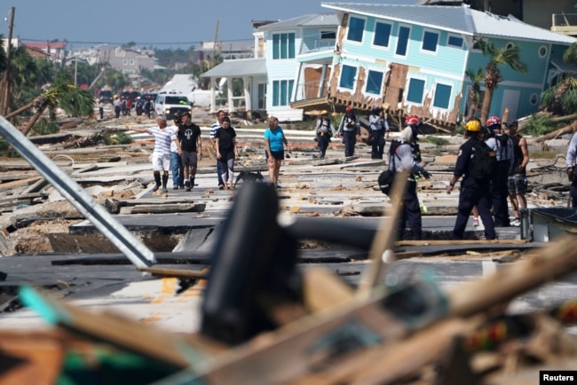 First responders and residents walk along a debris-littered street following Hurricane Michael, in Mexico Beach, Florida, Oct. 11, 2018.