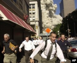 FILE - People run from a cloud of debris from the collapse of a World Trade Center tower in New York, Sept. 11, 2001.