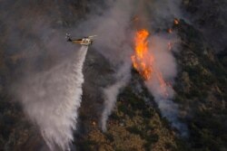 Un helicóptero derrama agua sobre uno de los cientos de incendios que se han reportado en días recientes en California. Según las autoridades, la ola de calor ha influido mucho para que se propague el fuego y dificulta el trabajo de los bomberos.