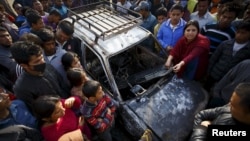 People gather around a taxi burned by protesters during a nationwide strike organized by the opposition alliance to demand the new constitution be drafted with the consensus of all political parties, in Kathmandu April 7, 2015. 