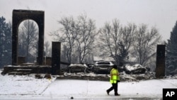 A worker walks past a destroyed home in Louisville, Colorado, Dec. 31, 2021. A wind-whipped wildfire tore through the area, and authorities fear more than 500 homes were destroyed. 