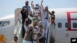 Tahanan Yaman mengepalkan tangan saat tiba di bandara di Sana'a setelah dibebaskan oleh koalisi pimpinan Saudi. (Foto: AP)