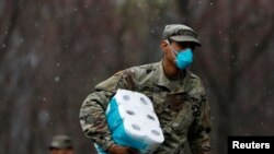 A member of Joint Task Force 2 wears a face mask while carrying paper towels in New Rochelle, New York, March 23, 2020.
