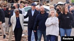 El presidente Joe Biden examina los daños causados por las tormentas y tornados mientras recorre un vecindario con la alcaldesa de Mayfield, Kathy O'Nan (der) y Anne Byfield (izq), presidenta del Consejo de Obispos en Kentucky, el 15 de diciembre de 2021.