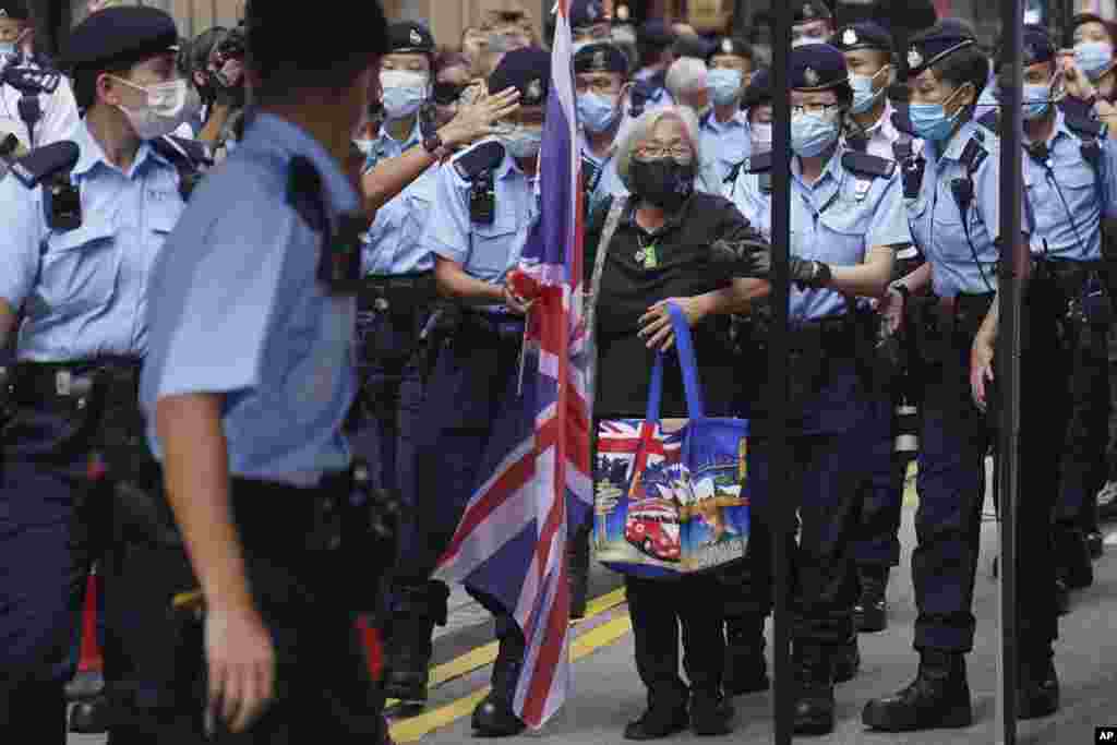 A protester holding a U.K. flag is arrested by police officers during the 24th anniversary of Hong Kong handover to China at a street in Hong Kong.