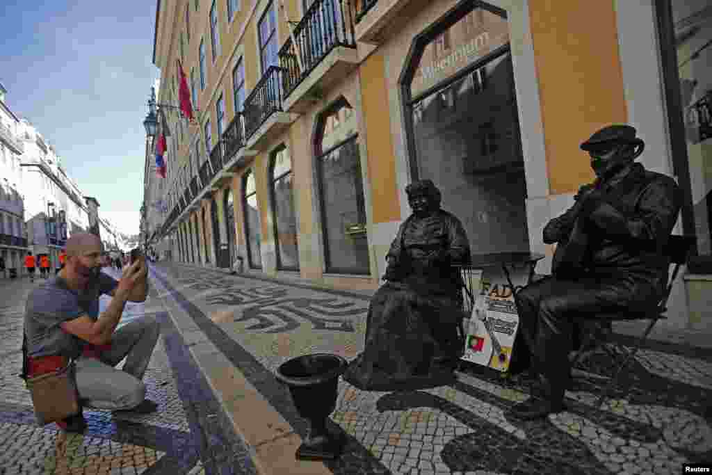 A man takes photos of performers near Portugal's Millennium BCP bank headquarters in Lisbon.