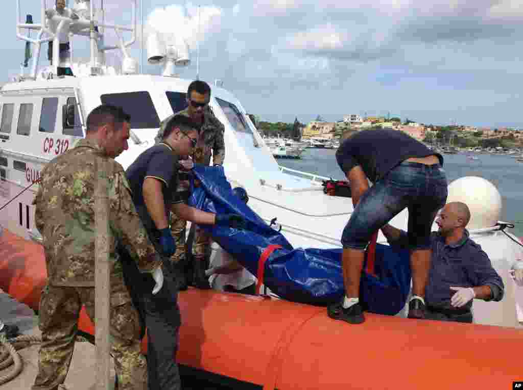 The body of a drowned migrant is being unloaded from a Coast Guard boat in the port of Lampedusa, Sicily, Oct. 3, 2013.