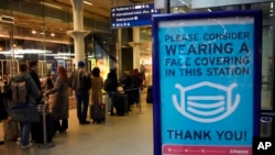 A sign asking people to wear face coverings to curb the spread of coronavirus is displayed at London St Pancras International rail station, in London, the Eurostar hub to travel to European countries, Dec. 17, 2021. 