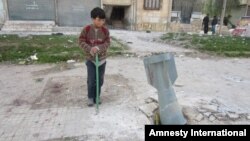 A child looks at the tail fin of a Russian-made RBK bomb that crashed through a sidewalk in a densely populated neighborhood east of Aleppo’s city center, March 1, 2013. 