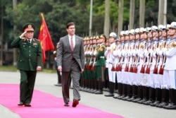 FILE - U.S. Defense Secretary Mark Esper, center, and Vietnamese Defense Minister Ngo Xuan Lich review an honor guard in Hanoi, Vietnam, Nov. 20, 2019.