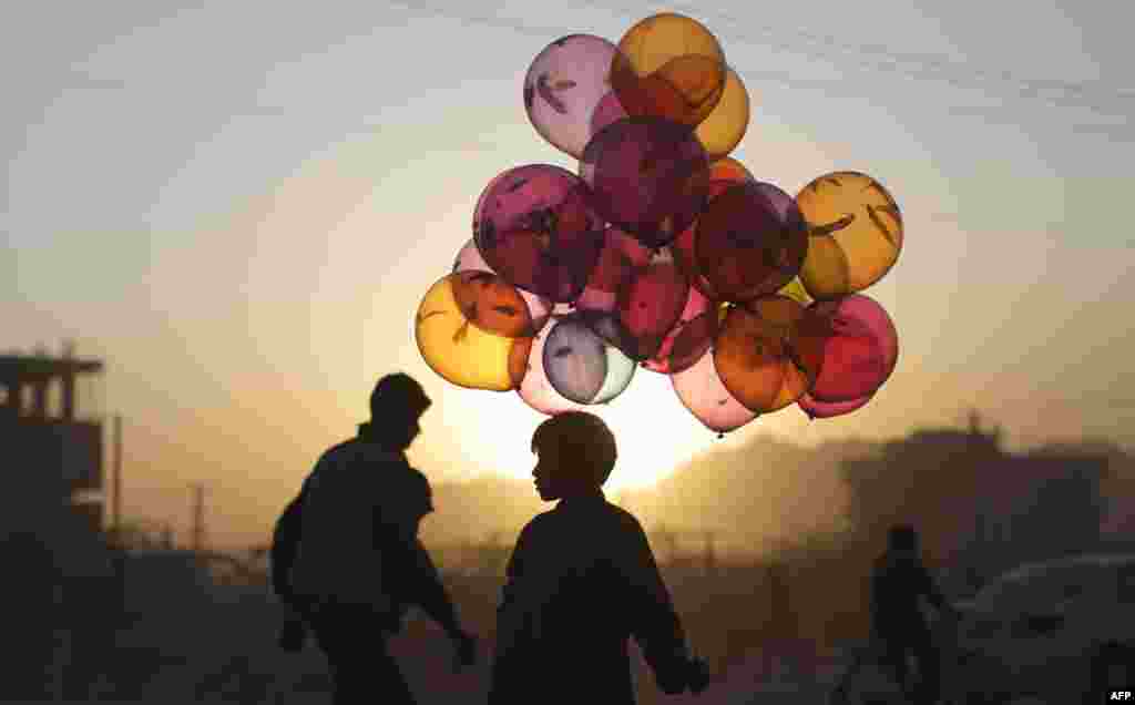 October 18: Afghan boy Mahfouz Bahbah, 12, stands on a roadside hoping to sell his balloons during sunset in Kabul, Afghanistan. AP Photo/Muhammed Muheisen)