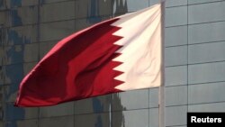 FILE - Qatar's flag flies in front of the Qatar National Bank's head office building in Doha, Nov. 30, 2009.