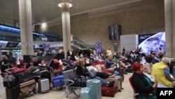 مسافران در فرودگاه بن گوریون تل آویومنظر پرواز‌هایشان نشسته‌اند.