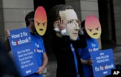 FILE - A protester wearing a mask with the face of Facebook founder Mark Zuckerberg, in between men wearing angry face emoji masks, is seen during a demonstration against Facebook outside Portcullis in London, April 26, 2018.