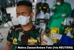 Reaksi seorang tentara saat disuntik vaksin COVID-19 buatan Sinovac Biotech di sebuah rumah sakit militer, di Palangka Raya, Kalimantan Tengah, 9 Maret 2021. (Foto: Makna Zaezar/Antara Foto via Reuters)