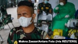 Reaksi seorang tentara saat disuntik vaksin COVID-19 buatan Sinovac Biotech di sebuah rumah sakit militer, di Palangka Raya, Kalimantan Tengah, 9 Maret 2021. (Foto: Makna Zaezar/Antara Foto via Reuters)