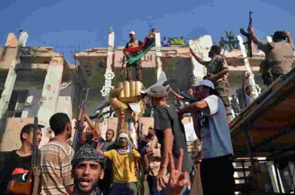 Rebels and their supporters celebrate around the iconic statue of a golden fist crushing a US military bomber outside Libyan leader Moammar Gadhafi's heavily damaged Bab al-Azizya compound in the centre of Tripoli on August 24, 2011