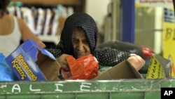 A woman collects goods from a garbage bin outside a supermarket in Thessaloniki, Greece, July 3, 2012. 