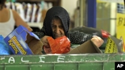 Một phụ nữ tìm những gì có thể nhặt được trong thùng rác bên ngoài một siêu thị ở Thessaloniki, Hy Lạp