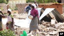 FILE: A woman salvages some bricks from her home after it was demolished by a bulldozer, Harare, Tuesday, Oct. 16, 2012. (AP Photo/Tsvangirayi Mukwazhi)