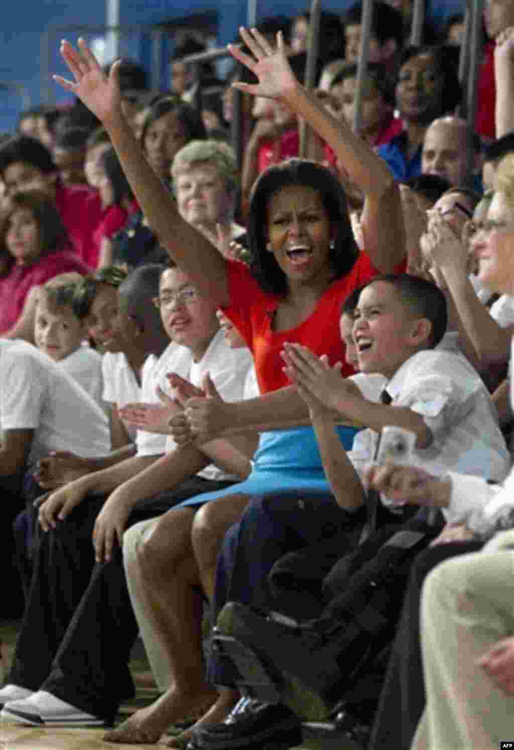 First lady Michelle Obama cheers with students from Nancy Moseley Elementary School during a Let's Move event with members of Bravo's series "Top Chef" Friday, Feb. 10, 2012, at Kleberg Rylie Recreation Center in Dallas, during her three day national tour