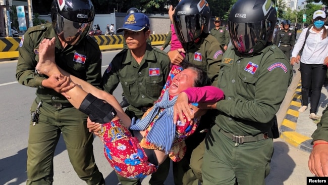 在中国驻金边大使馆外柬埔寨警察抬走一名抗议中国在柬埔寨设立军事基地计划的妇女。(2020年10月23日)