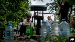 Local citizens line up to collect water, in a street in the center of Slovyansk, eastern Ukraine, July 13, 2014.