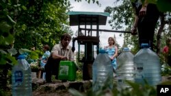 Local citizens line up to collect water, in a street in the center of Slovyansk, eastern Ukraine, July 13, 2014.