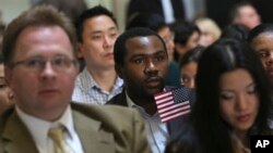 Zoltan Sznorfi, left, originally from Hungary, Benjamin Njoku, center, originally from Nigeria, and Keyan Chen, right, originally from China wait for the naturalization ceremony at historic Federal Hall to start, Friday, March 22, 2013 in New York.