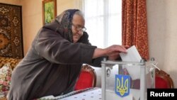 A local resident casts a vote into a mobile ballot box inside a house during a presidential election in the village of Zahiria in Lviv Region, Ukraine, March 31, 2019. 