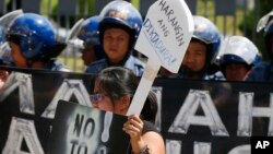 A protester displays her message during a rally at the Heroes Cemetery to protest the interment on its grounds last year of late Philippine dictator Ferdinand Marcos, as the nation marks the 31st anniversary of the People Power revolution that ended his 20-year-rule, Feb. 25, 2017, in suburban Taguig city, east of Manila, Philippines.The placard reads: "Block Dictatorship!"