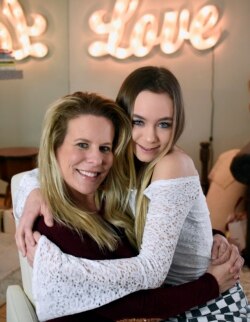 In this Feb. 28, 2018 photo, Matty Nev Luby, right, and her mother Kerrylynn Mahoney pose together for a photograph in Wethersfield, Conn. The high school gymnast’s popularity on the lip-syncing app Musical.ly, which merged this summer into the Chinese vi