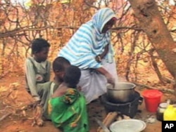 A woman prepares a meal for several children. There is no electricity or running water in homes, and food often is in short supply at the Kakuma Refugee Camp, Aug 2010