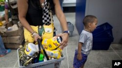 FILE - A shopper in a Caracas supermarket holds her basket of products that have been in short supply, Feb. 3, 2015.