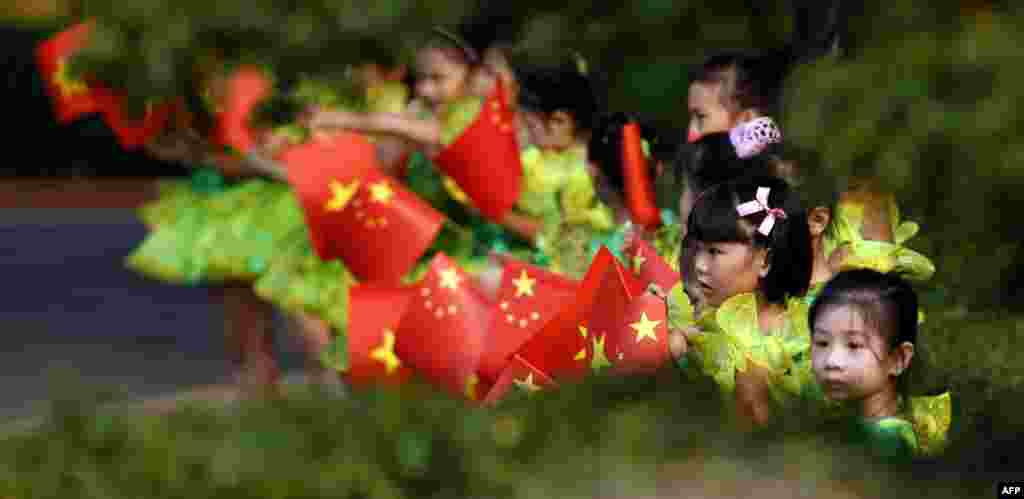 Schoolgirls wave Vietnamese and Chinese flags before a welcoming ceremony for Chinese Premier Li Keqiang at the Presidential Palace in Hanoi. Li is in Hanoi on a three-day visit to Vietnam from October 13 to 15, photo taken Oct. 13, 2013.