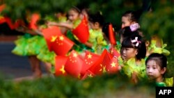 Schoolgirls wave Vietnamese and Chinese flags before a welcoming ceremony for Chinese Premier Li Keqiang at the Presidential Palace in Hanoi, Oct. 13, 2013.