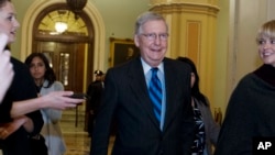 Senate Majority Leader Mitch McConnell, R-Ky., listens to questions from reporters as he walks to his office after speaking on the Senate floor at the Capitol, Sunday, Jan. 21, 2018, in Washington.