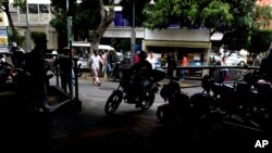 Moto-taxi drivers wait for clients at their station, April 7, 2016, near the site where a Venezuelan man was beaten and burned alive after he was accused of stealing the equivalent of $5 in Caracas. Vigilante violence against people accused of stealing has become commonplace. 