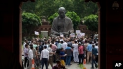 Media personnel surround opposition lawmakers protesting near a Mahatma Gandhi statue on Parliament premises in New Delhi, India, Aug. 6, 2015.