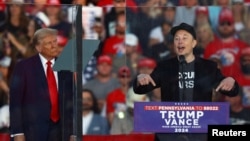 FILE - Billionaire Elon Musk speaks as Republican presidential nominee and former U.S. President Donald Trump looks on during a rally in Butler, Pennsylvania, on Oct. 5, 2024.