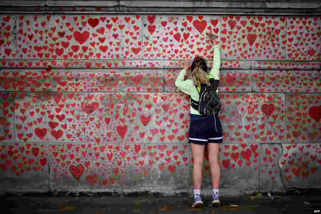 A woman draws on the National Covid Memorial Wall on the embankment on the south side of the River Thames in London.