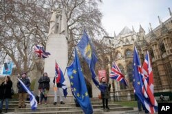 FILE - Anti-Brexit demonstrators wave flags outside the houses of Parliament in London, Britain, Dec. 19, 2018.
