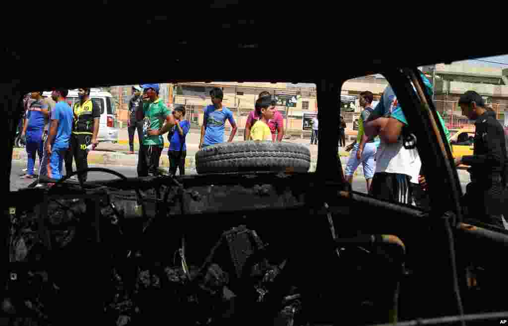 Civilians inspect the site of a car bomb explosion in the Shi'ite stronghold of Sadr City, in Baghdad, May 13, 2014. 