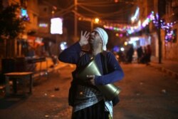 Seorang Mesaharati Palestina memegang drum saat dia membangunkan warga muslim untuk sahur selama bulan suci Ramadan, di tengah pandemi COVID-19, di Khan Younis di Jalur Gaza selatan, 15 April 2021. (REUTERS / Ibraheem Abu Mustafa)