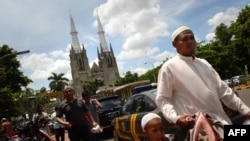 Seorang pria Muslim tiba di masjid Istiqlal yang terletak di seberang Katedral di Jakarta.