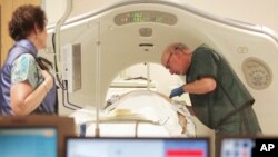 FILE - A physician uses a CT scanner to screen a patient for lung cancer at Southern New Hampshire Medical Center in Nashua, June 3, 2010.