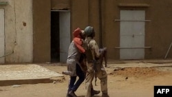 Seorang anggota pasukan keamanan Mali menggendong seorang anak yang terluka dalam serangan bom di Gao, 1 Juli 2018.(Foto: AFP)