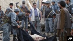 Afghan police officers wrap the body of a hotel guard in a black cloth after a suicide attack in Kunduz, north of Kabul, Afghanistan, August 2, 2011