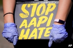 FILE - A woman holds a sign and attends a rally to support stop AAPI (Asian Americans and Pacific Islanders) hate at the Logan Square Monument in Chicago, March 20, 2021.